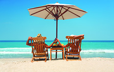 couple holding hands in lounge chairs on beach under umbrella